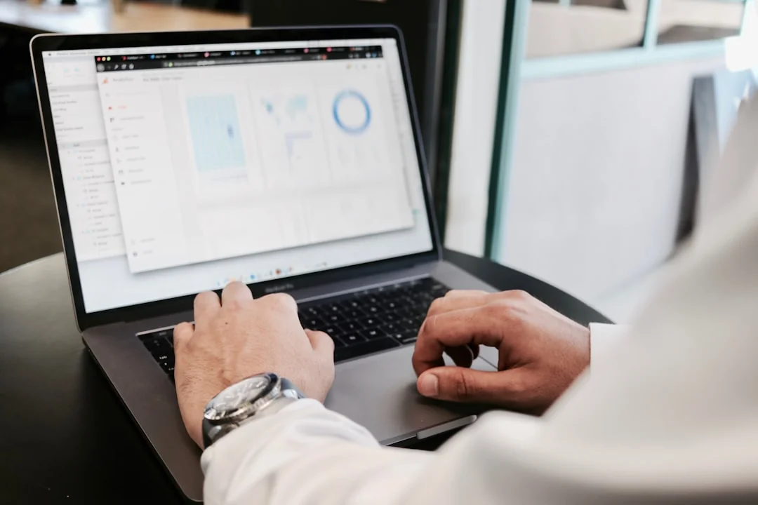 A modern workspace showing hands analyzing marketing data on a laptop and paper documents.